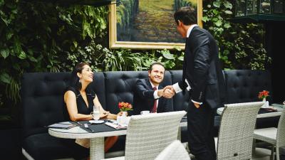 565330257 Smiling businessmen shaking hands before sitting down at table for meeting with business executives in restaurant